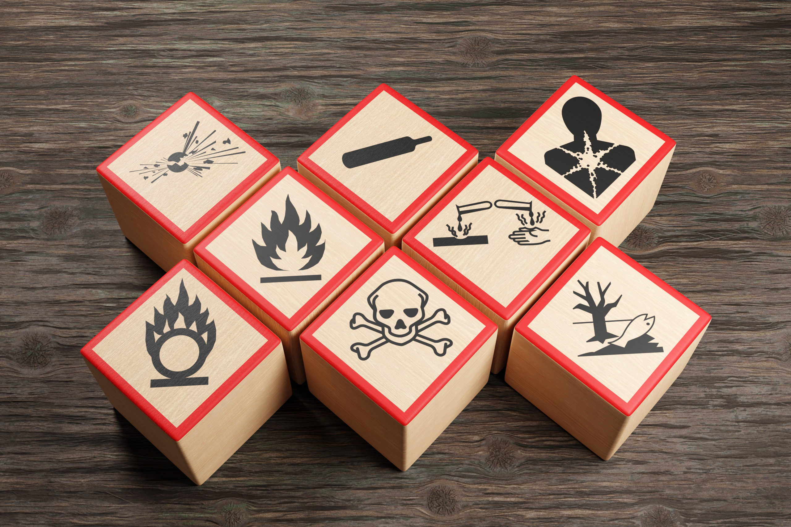 Wooden blocks showing different symbols of chemical hazard warnings on wood table. Illustration of the concept of toxic substances and occupational health