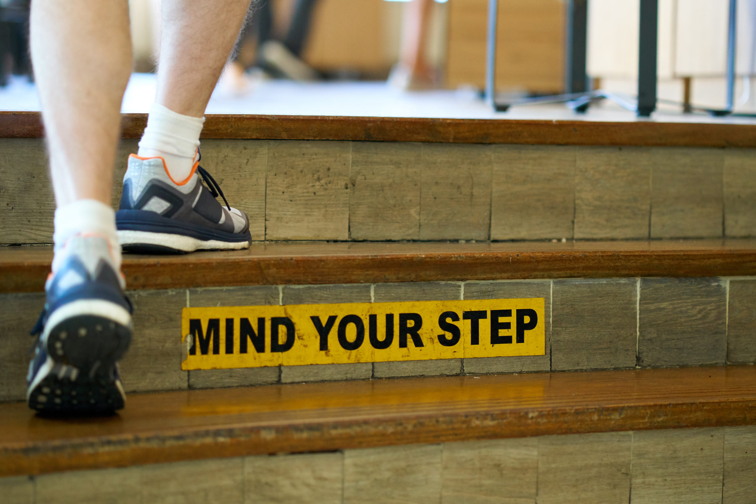 Man walking up the stairs with"Mind your step" safety caution si